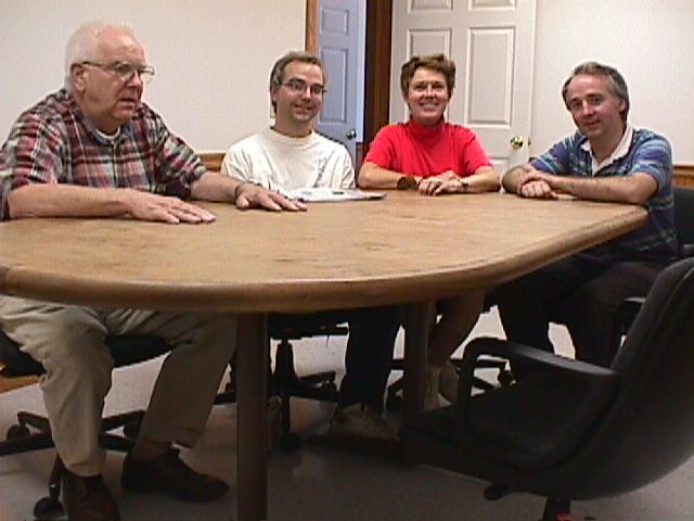 Bill, Clifford, Shirley, and Dean sit at a conference table